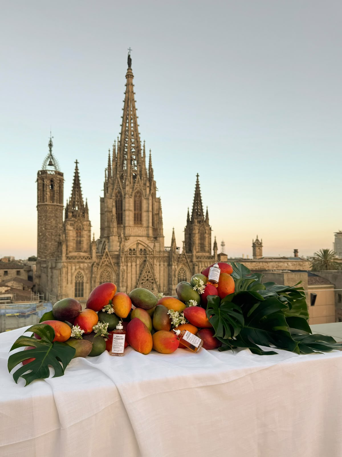 Composición de fruta tropical y hojas frente a una catedral al atardecer
