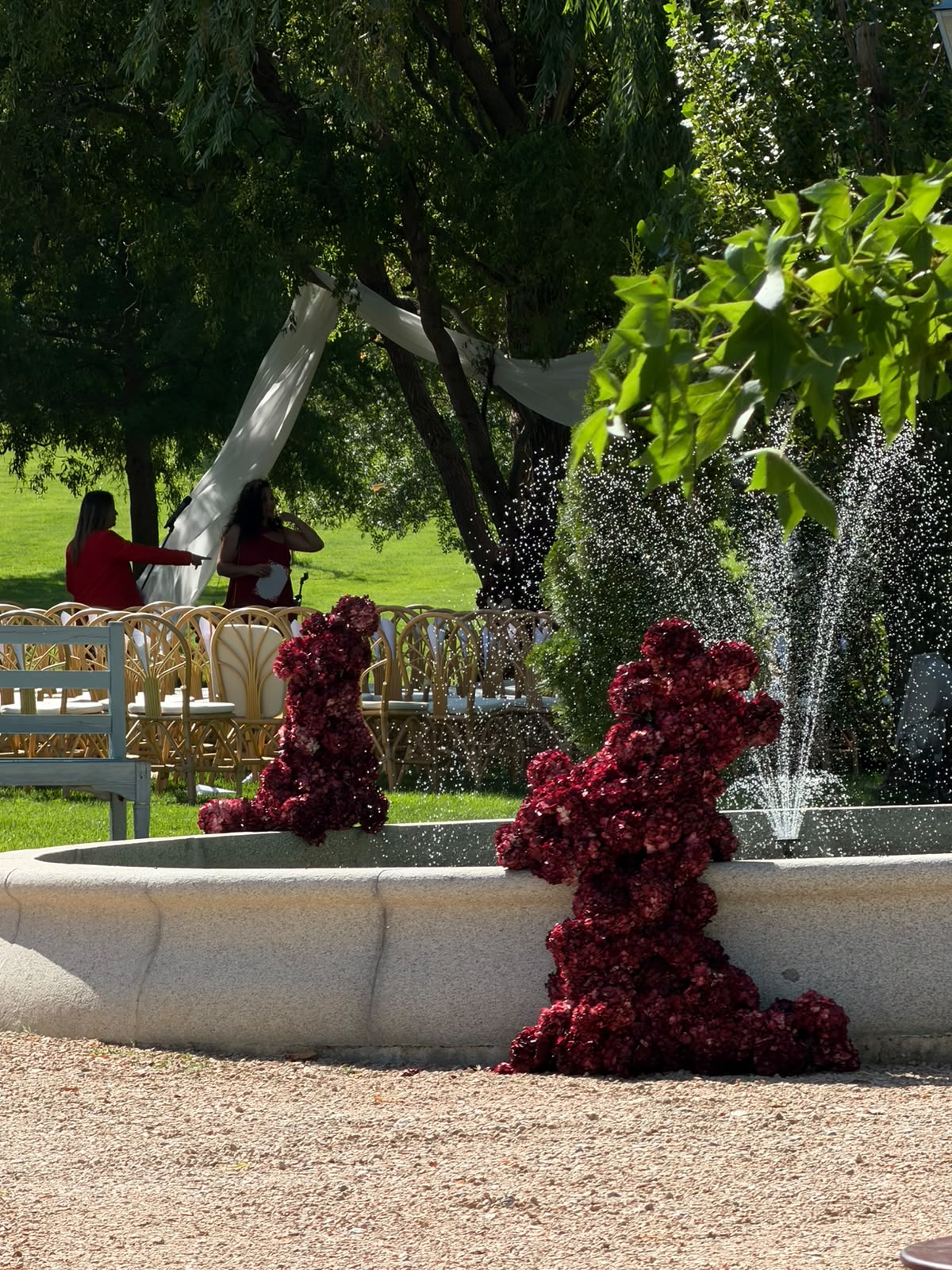 Estructuras florales burdeos alrededor de una fuente en una ceremonia de boda