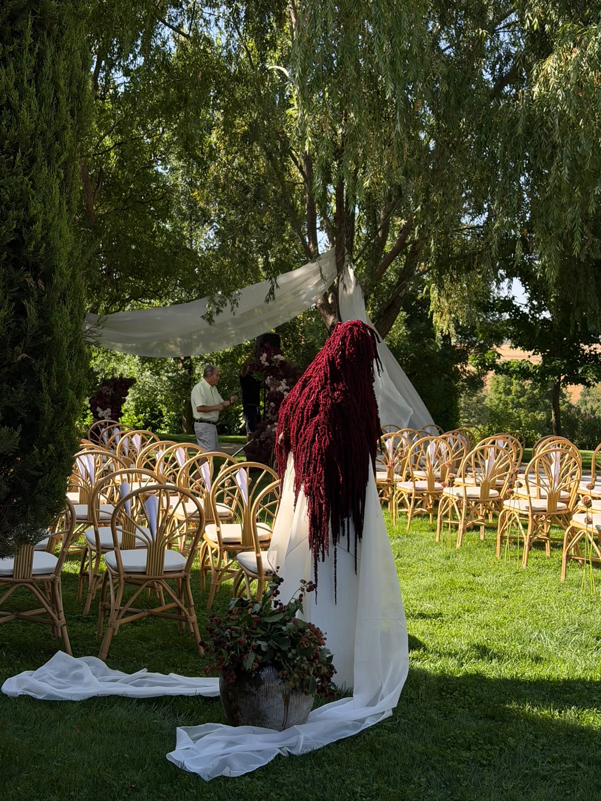 Figura floral burdeos entre las sillas de una ceremonia de boda en un jardín